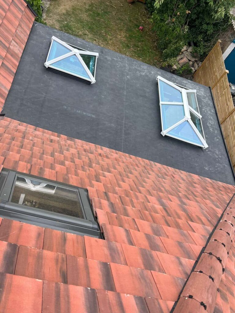 This is a photo taken from the roof ridge looking down a tiled pitched roof on to a flat roof. Works carried out by LJ Roofing Pewsham